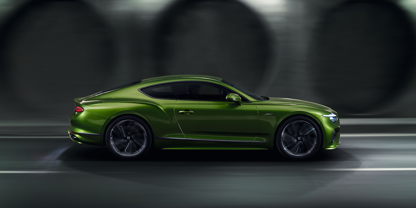Bentley Auckland Bentley Continental GT coupe in Tourmaline Green paint driving in profile on a dark road