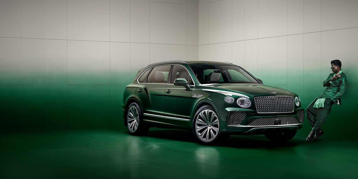 Bentley Auckland Wisdom K leans against wall next to Bentley Bentayga Extended Wheelbase Atelier Edition SUV in Light Emerald green paint