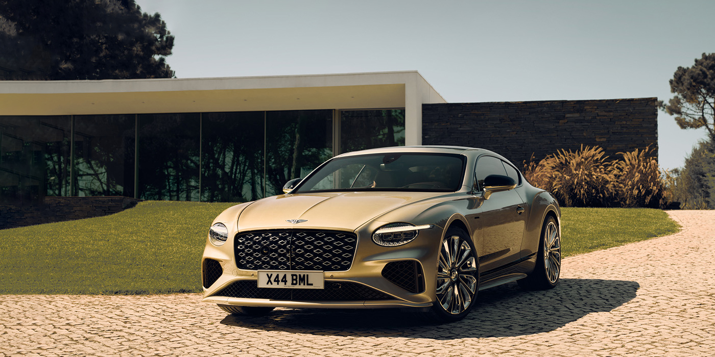 Bentley Auckland Bentley Continental GT Mulliner coupe front three quarters in Patina paint parked outside a glass fronted building with a grass lawn behind it